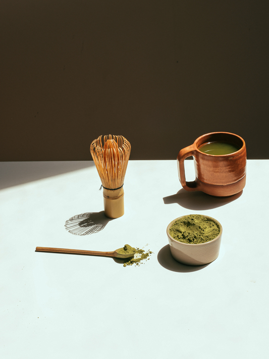 Bright green matcha powder with bamboo whisk.